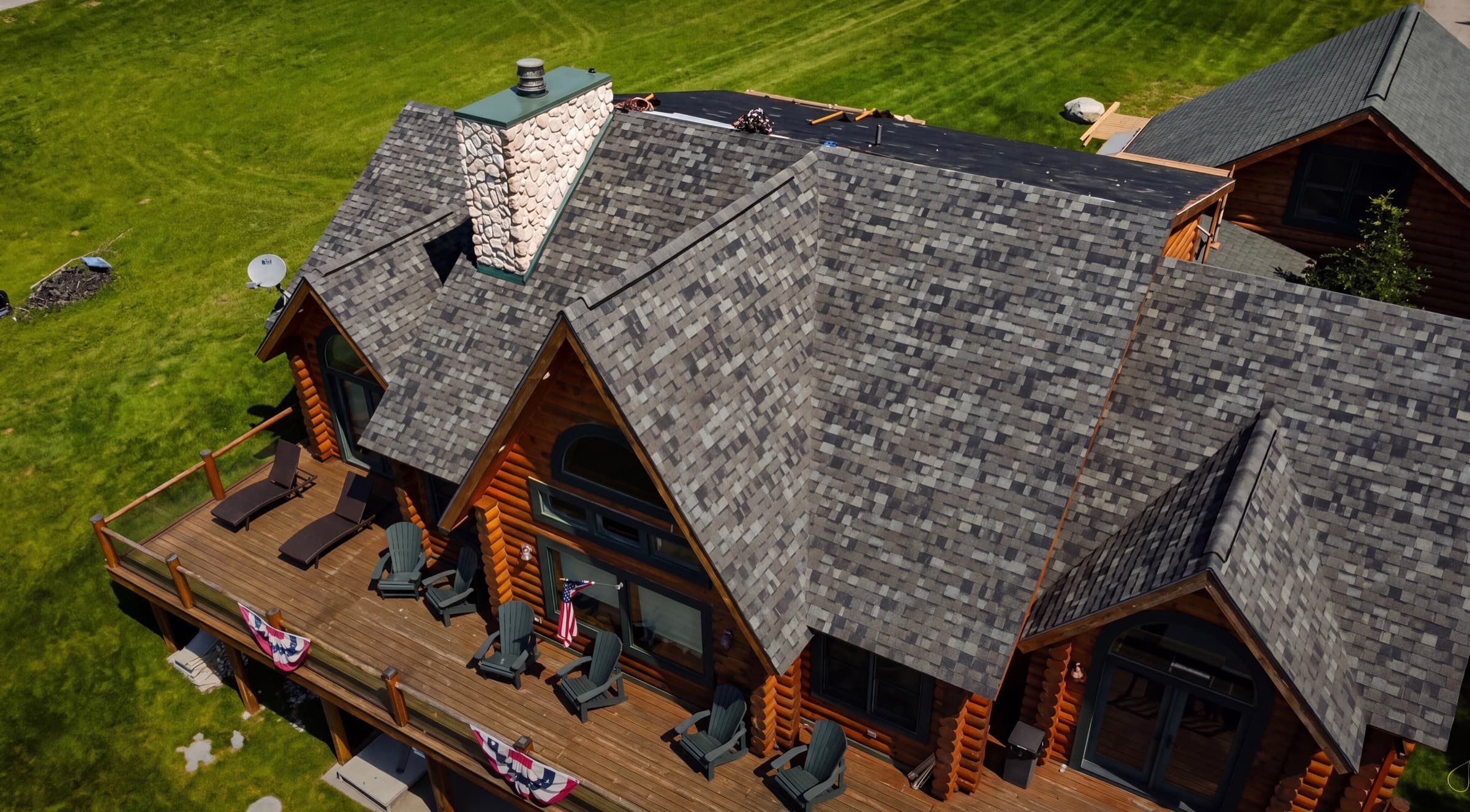 Aerial view of a Lemieur Roofing project — multi-pitch architectural shingle roof on a Northern Michigan timber home with a wraparound deck